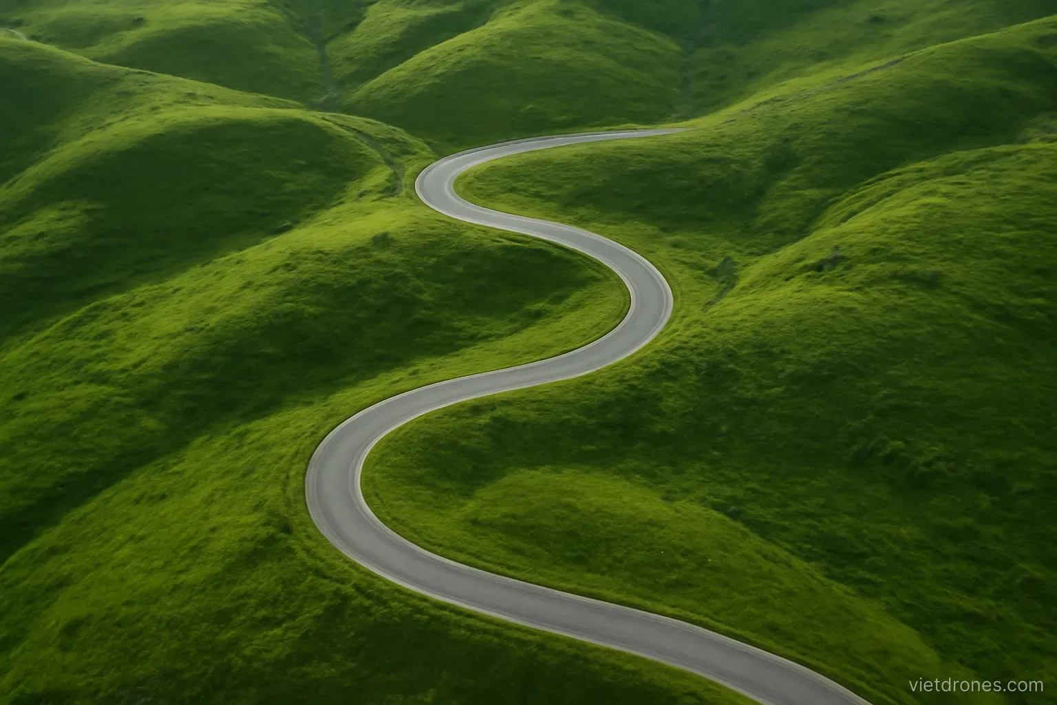 An aerial view of a winding road through green hills